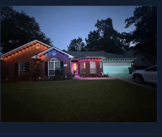 Single-story brick ranch lit at night with multicolor Govee Permanent Outdoor Pro pucks running across the front roofline and gables — installed in GeauxTrax PETG track.