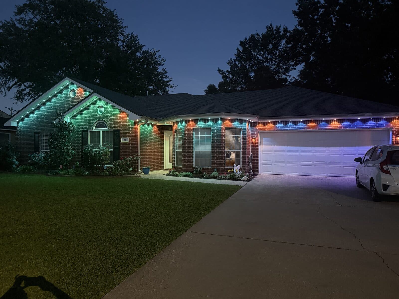 Govee Permanent Outdoor Pro installed on single-story brick home with GeauxTrax PETG track, displaying a green and blue color scene across the roofline at dusk